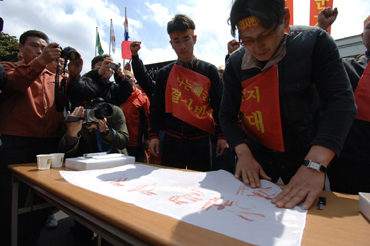 6일 해군기지건설 반대를 주장하는 위미리주민들이 항의시위가 열린 가운데 이 마을 청년회장이 혈서를 쓰고 있다.   <박민호 기자>