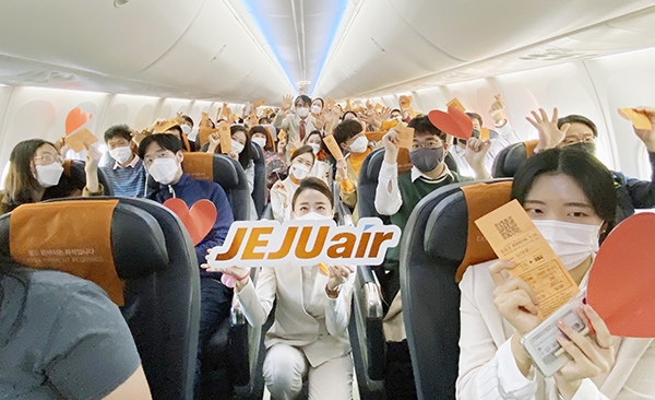 23일 오후 인천국제공항을 출발해 인천국제공항으로 돌아오는 제주항공7C380편 기내에서 일반인 대상 첫 '관광비행(하트시그널 비행)'을 기념해 승객들과 함께 기념사진을 찍고 있다.
