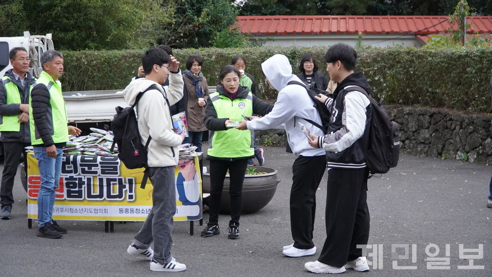 16일 서귀포고등학교 앞에서 동홍동청소년협의회 회원들이 수험생들에게 핫팩과 간식 등 응원 선물을 나눠주고 있다. 고기욱 기자