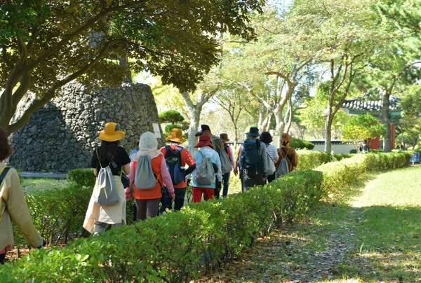시민과 관광객들이 녹음이 우거진 '성안올레'를 제주성의 성벽을 따라 걷고 있다.