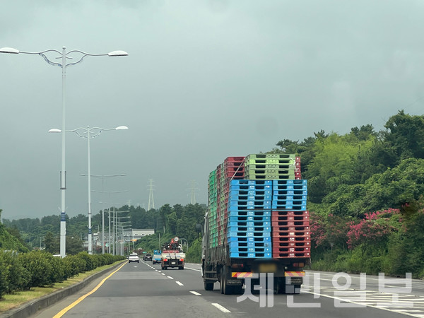 21일 제주시 평화로 인근 도로에서 한 화물차가 여러 개의 파레트를 안전하게 적재하지 않은 채 주행하는 등 아찔한 상황을 연출하고 있다. 전예린 기자 