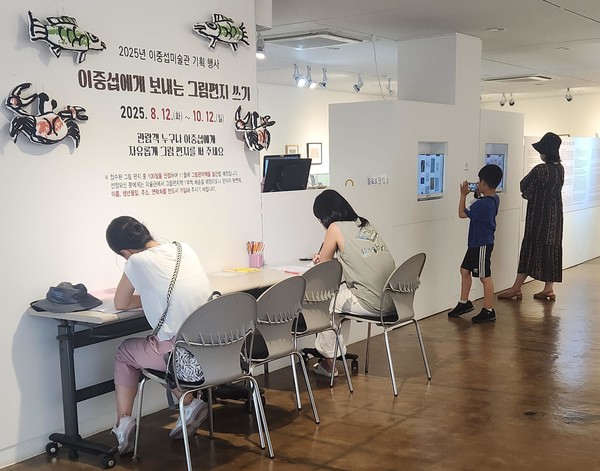 이중섭 미술관을 찾은 방문객들이 이중섭에게 보내는그림편지를 쓰고 있다.